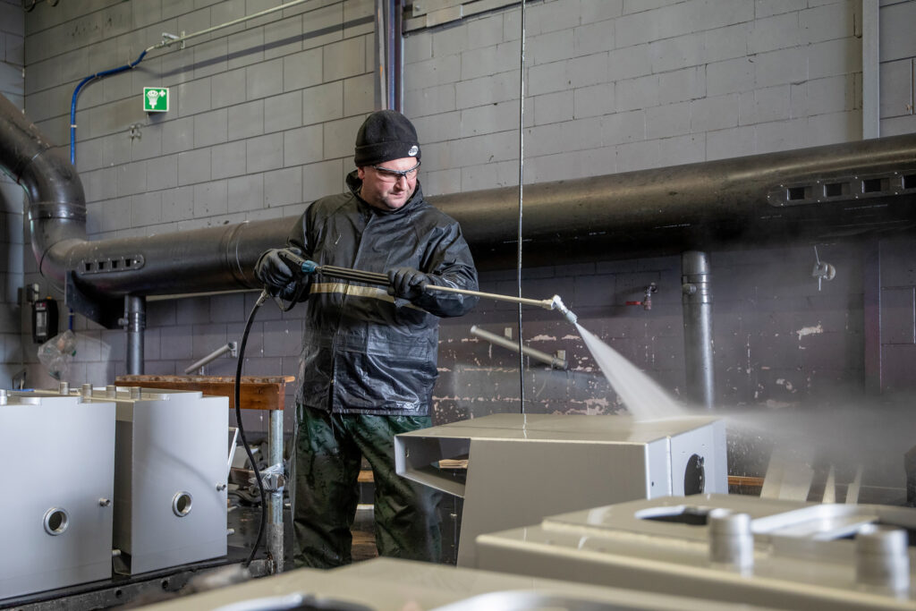 Medewerker spuit osmozewater om beits op rvs constructie af te spoelen.