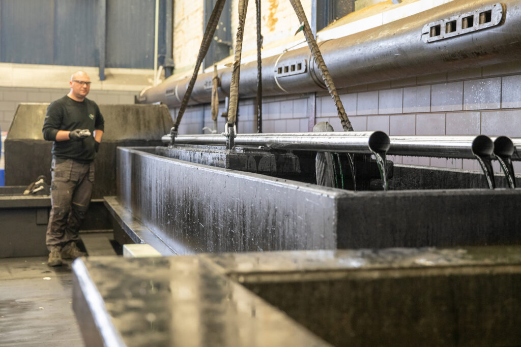 Rvs onderdelen worden ondergedompeld in een beitsbad tijdens het badbeitsproces bij BMN Lopik